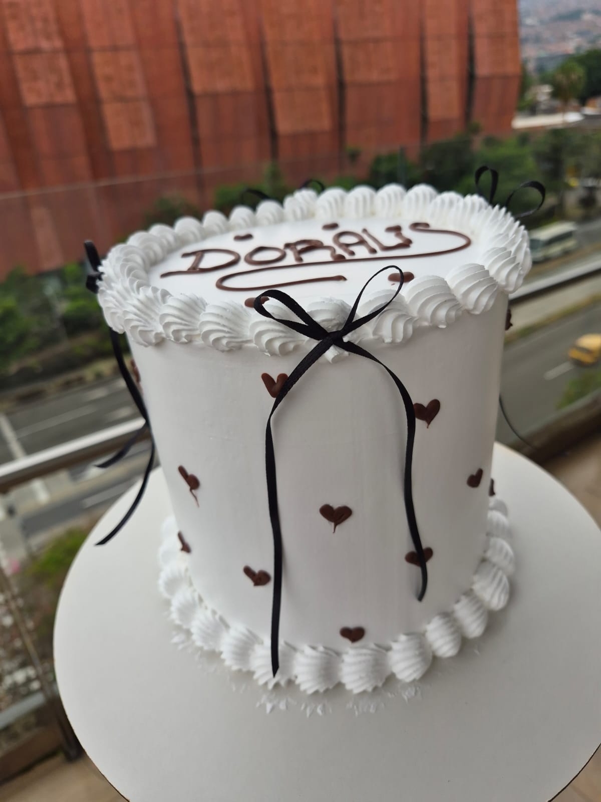 Torta blanca con lazos negros y pequeños corazones